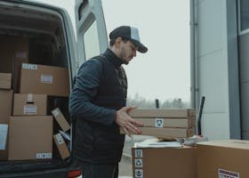 Delivery driver handling cardboard boxes during shipping at a commercial building.